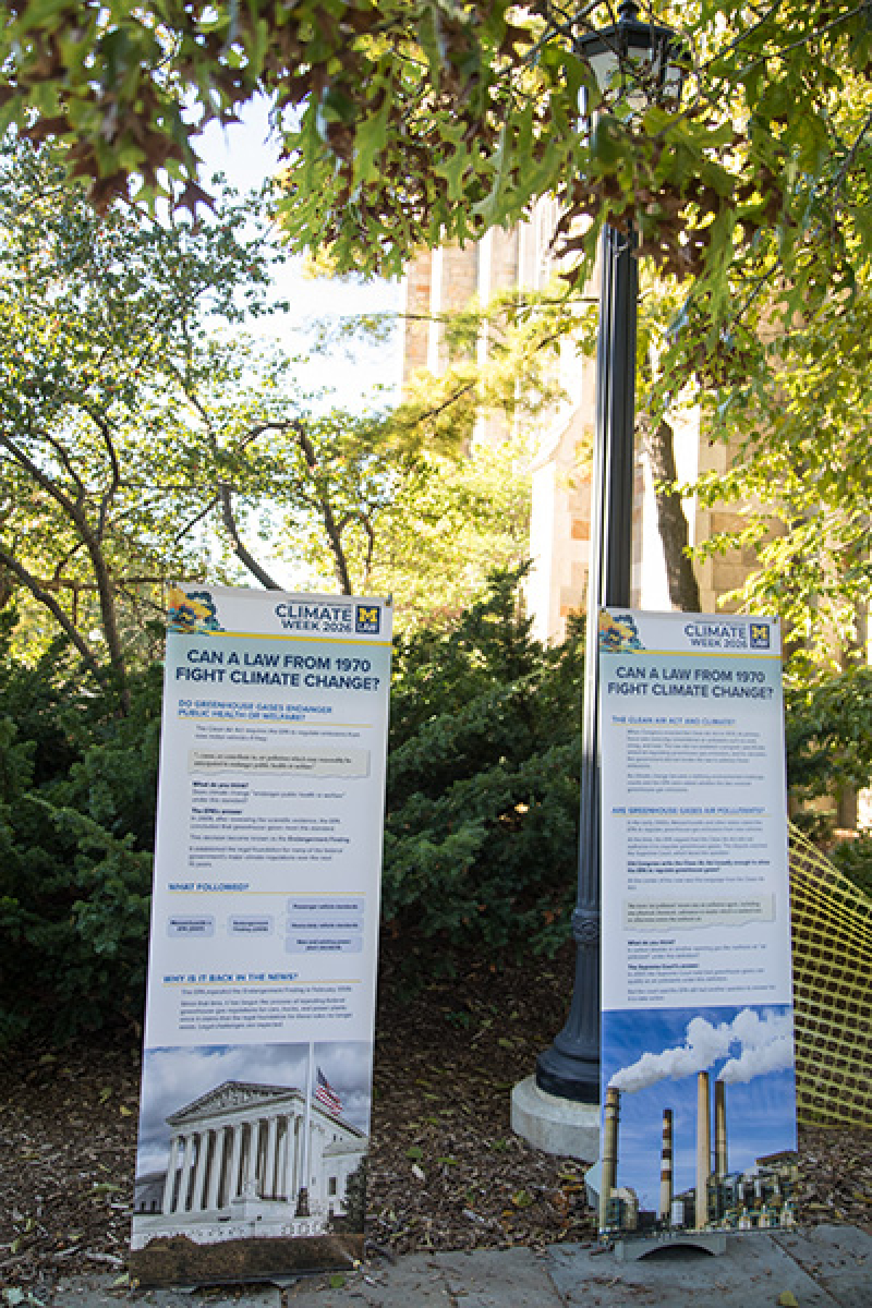 Two Climate Week exhibits stand side-by-side under the shade of trees.