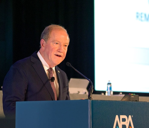 William R. Bay speaking to a crowd on a podium.