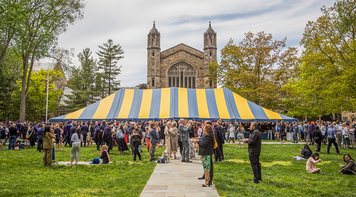 A large gathering of family and friends of Michigan Law graduates celebrate outside at the Michigan  Law Quadrangle.