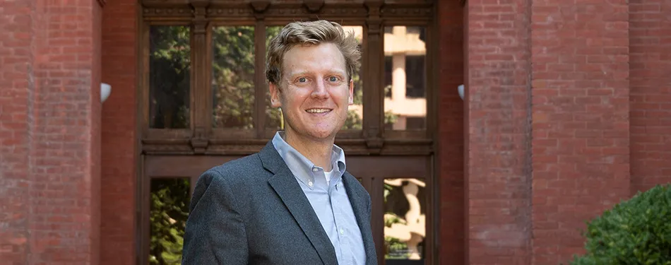 Professor Steven Schaus standing in front a red brick building