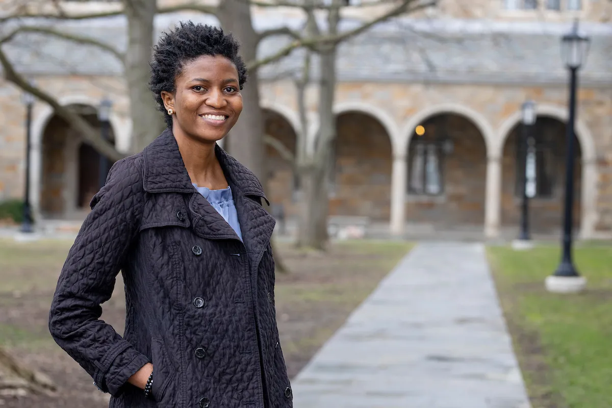 LLM student Abimboya Adekoya stands in the Law Quad with her hands in her coat pockets.