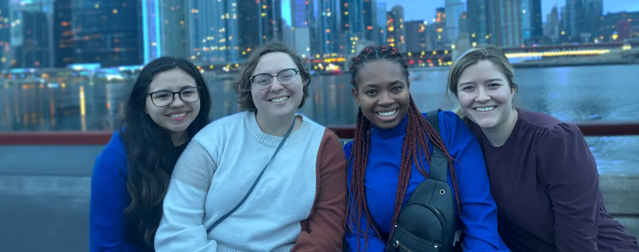 Four people smiling on a boat in front of Chicago's coastline
