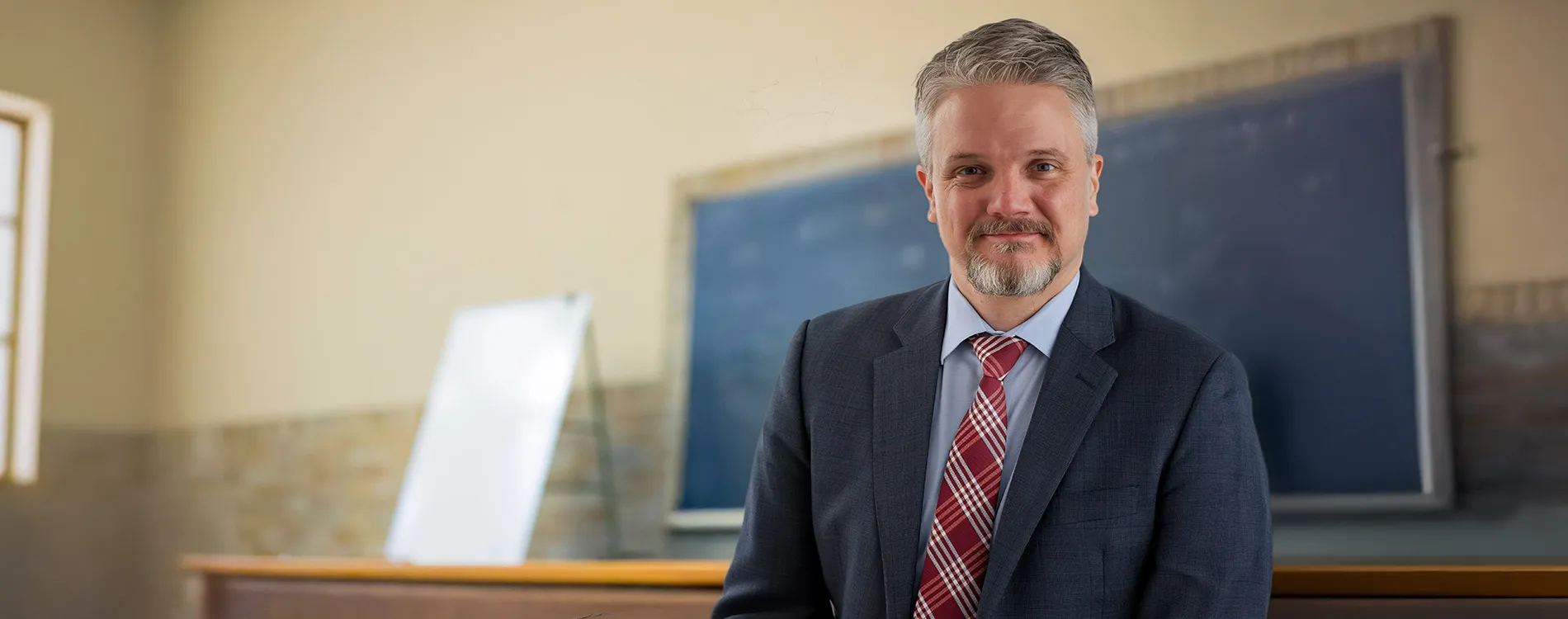 Julian Mortenson portrait in a classic Michigan Law classroom.
