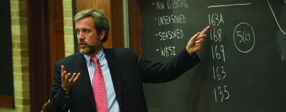 Nicholas Howson pointing at chalkboard as he teaches a class.