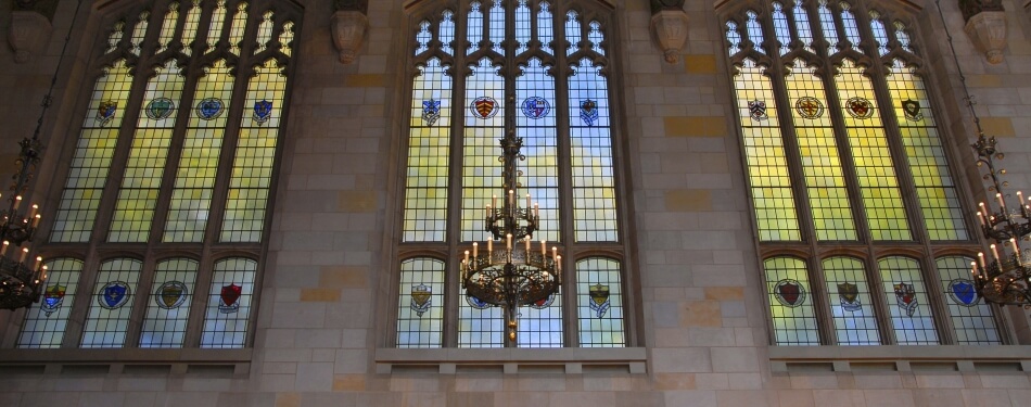 A view lookin up at a set of reading room windows with blue and gold light shining through