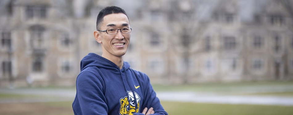 Takuji Shimizu stands with his arms crossed in the Michigan Law Quad.