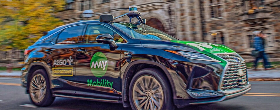 Action shot of an autonomously driven car passing in front of Michigan Law buildings