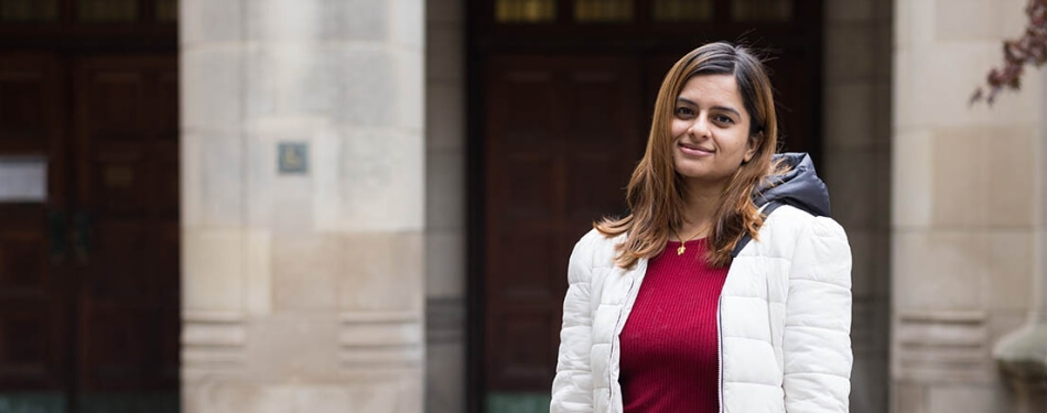 A woman in a windbreaker stands in the Law Quad.