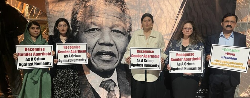 Five people stand in solidarity, holding signs that demand recognition of gender apartheid as a crime against humanity.