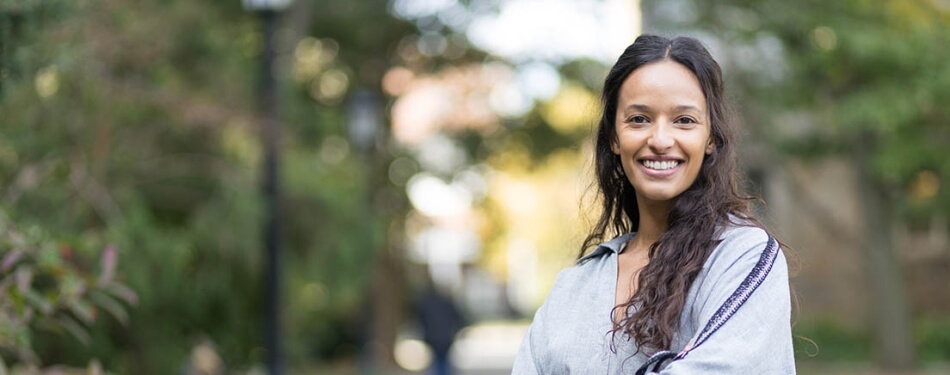 Camila Calvo smiles with arms crossed in the sunny Michigan Law quad.