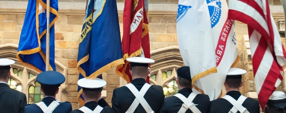 Members of the military holding flags during the launch of the Veterans Legal Clinic ceremony