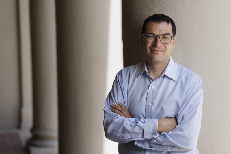 Professor Sam Erman leaning against a building column