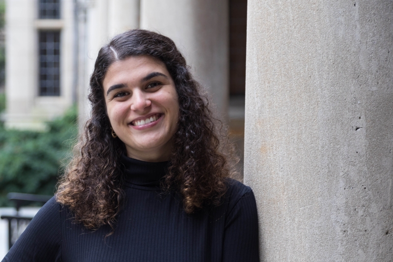 Fernanda Lopes De Alcantara Gil leans against a stone pillar in the Michigan Law quad.
