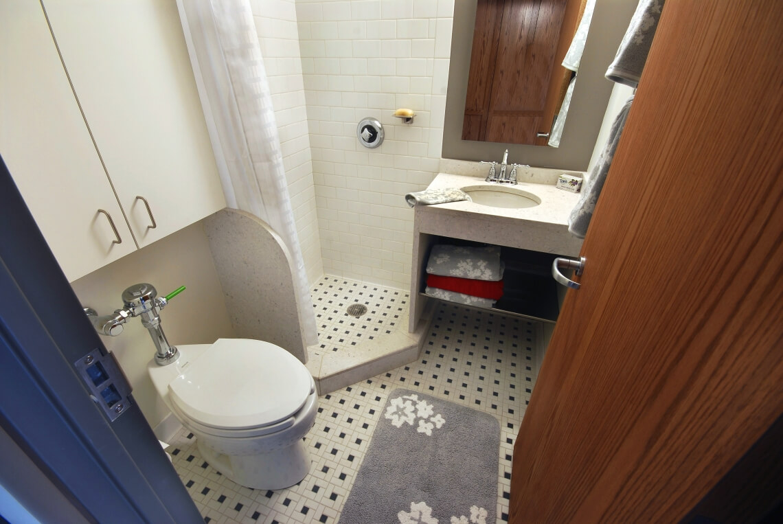 Tiled private bathrooms have a toilet, sink, shower, shower curtain, and cabinet.