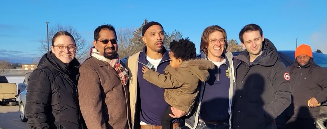 Donyelle Woods (center, holding his grandson) celebrates his newfound freedom with a few of the people who worked on his case at the Michigan Innocence Clinic: (from left) 3L Kate Thompson; Imran Syed, ’11, the clinic’s co-director; and Jake Aronson and Sam Winick, both 2Ls. Syed first began working on Woods’s case as a student-attorney just after the clinic opened in 2009.