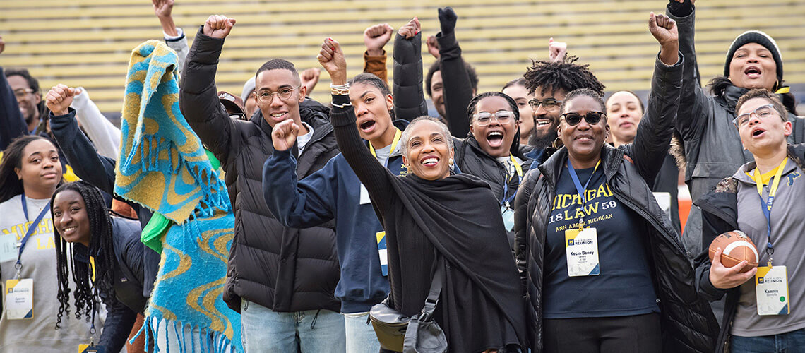 A group of Michigan Law alumni cheer on the field of Michigan Stadium.