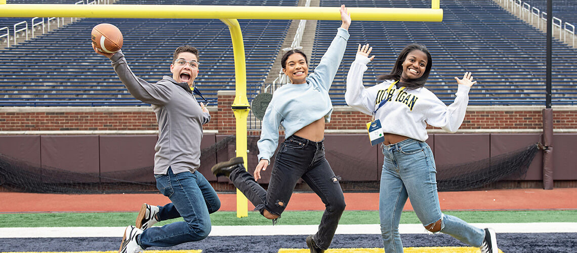 A group of Michigan Law alumni jumping on the Michigan Stadium field.