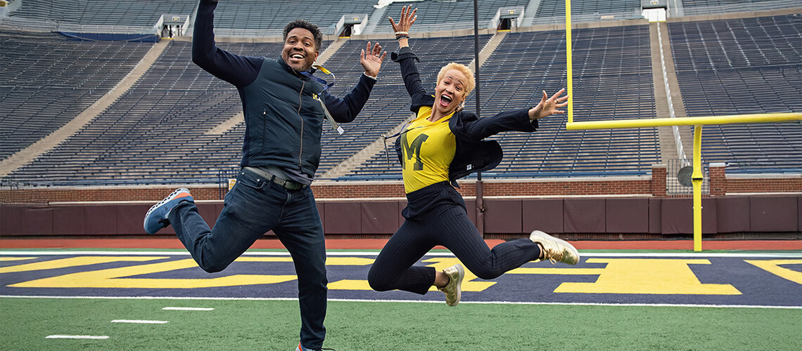 Mackenzie Phillips and fellow alumni jumping on the Michigan Stadium field.