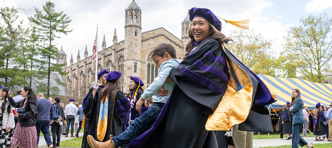 Michigan Law student holding their child after the Senior Day ceremony.