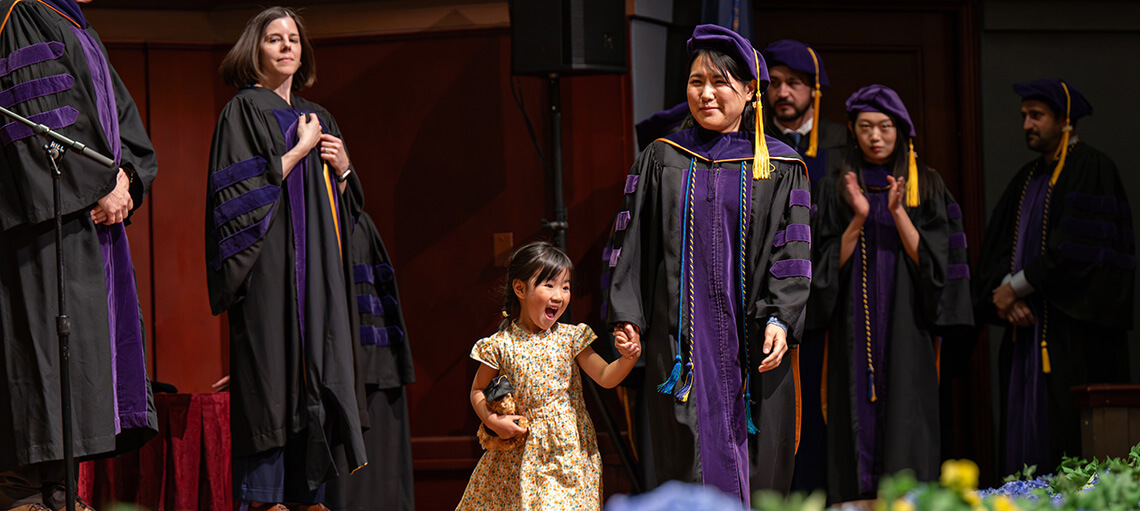 Michigan Law student walks across stage with child.