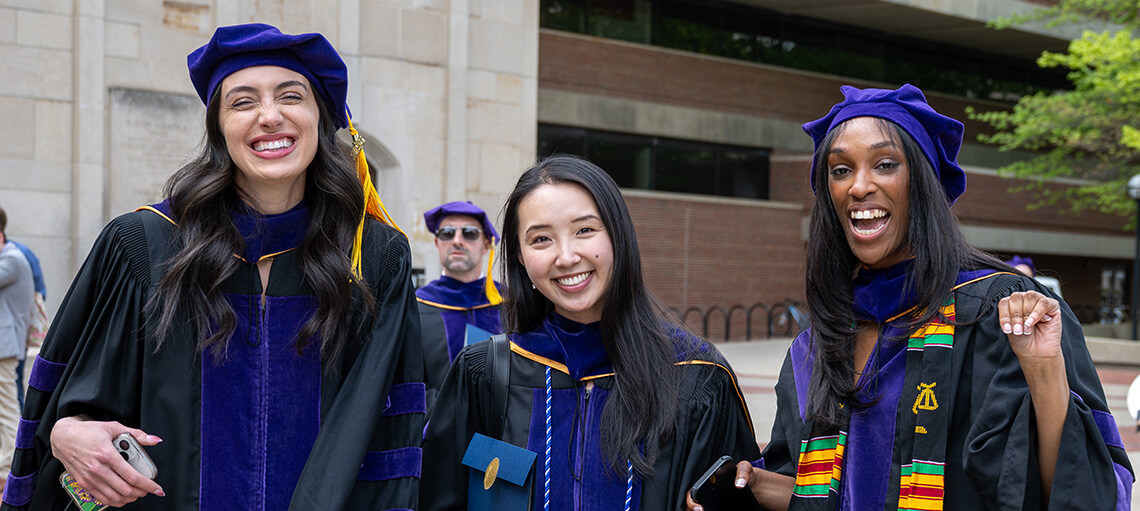 Three Michigan Law students outside Hill Auditorium before the Senior Day ceremony.