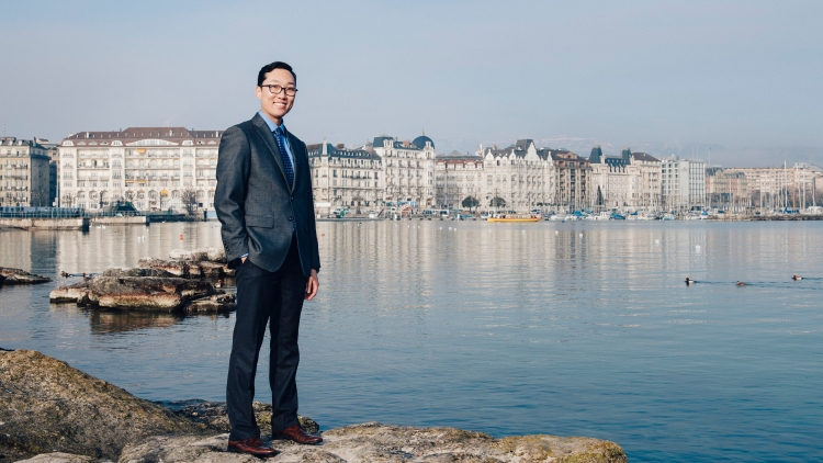 A suited man stands on a rock overlooking Lac Léman in Geneva, Switzerland.