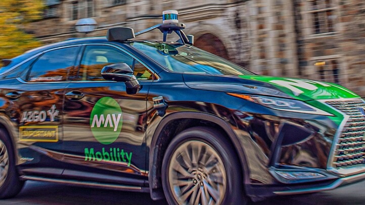 Action shot of an autonomously driven car passing in front of Michigan Law buildings