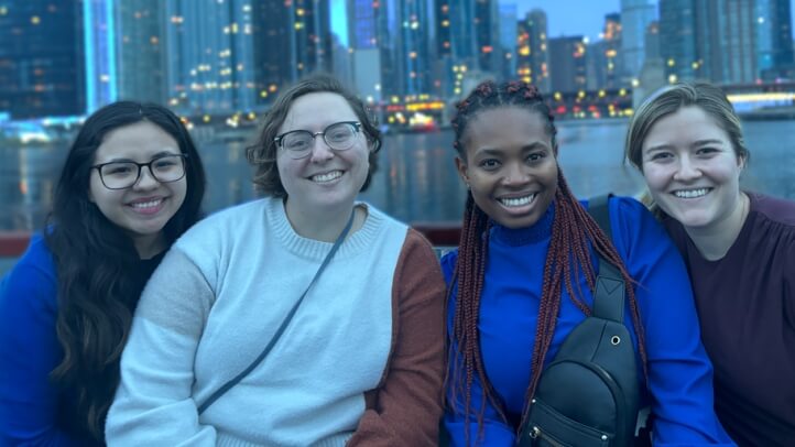Four people smiling on a boat in front of Chicago's coastline