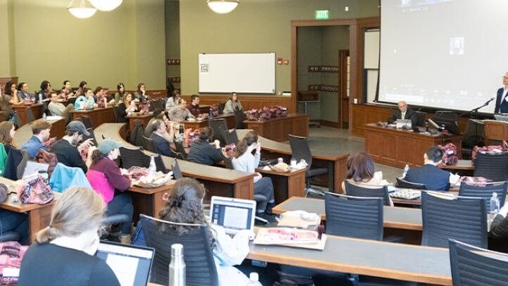 Two people lecturing to a packed auditorium at the university of Michigan law school.