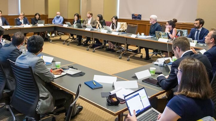 Participants gather around a table at a conference.