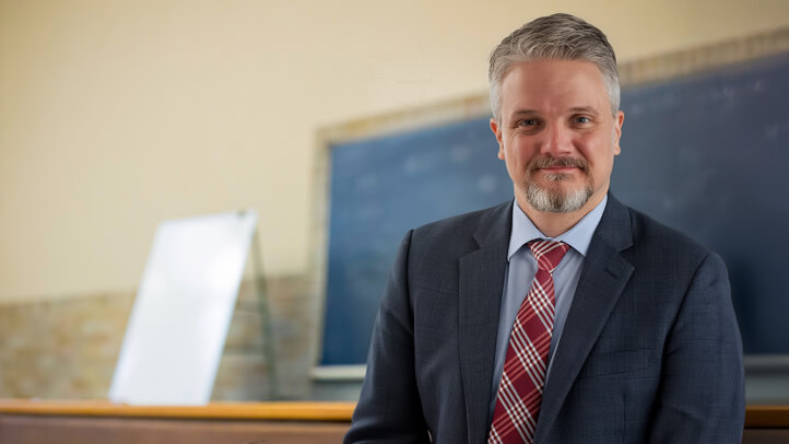 Julian Mortenson portrait in a classic Michigan Law classroom.