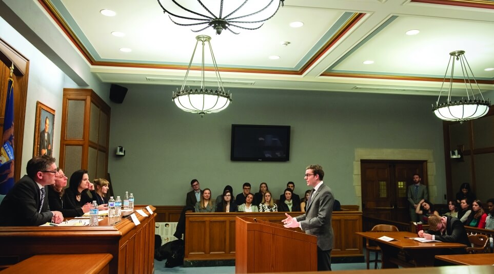 A student arguing a case at the podium in front of 4 judges in the moot court room.
