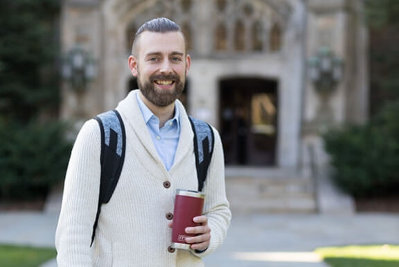 Jonathan Church holds a cup of coffee in the Law Quad.