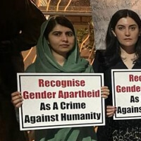Person holding a sign that reads Recognize Gender Apartheid As A Crime Against Humanity.