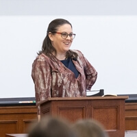 A person speaking at a podium during a lecture