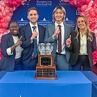 The Michigan Law Mock Trial Team from left to right, Joclyn Hutchison, Nat Jordan, Brian Tang, and Lauren Smith celebrate their win in front of their Capitol City Challenge (CCC) Mock Trial Competition trophy.